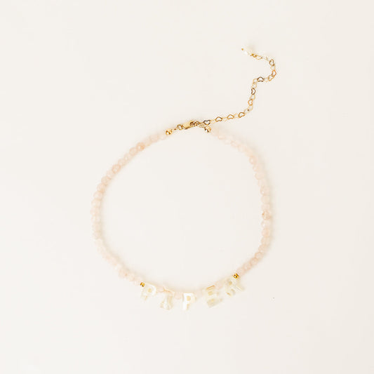 Gold bracelet with small beads on a light beige background