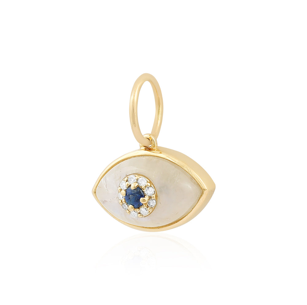 Gold evil eye pendant featuring a white mother-of-pearl inlay, a central blue sapphire, and a halo of small clear crystals, shown on a white background with a soft reflection.