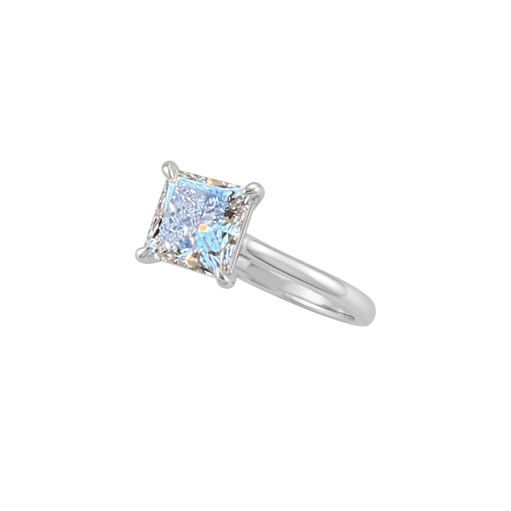 Angled view of a princess-cut diamond engagement ring with four corner prongs and a polished white-metal band on a white background.