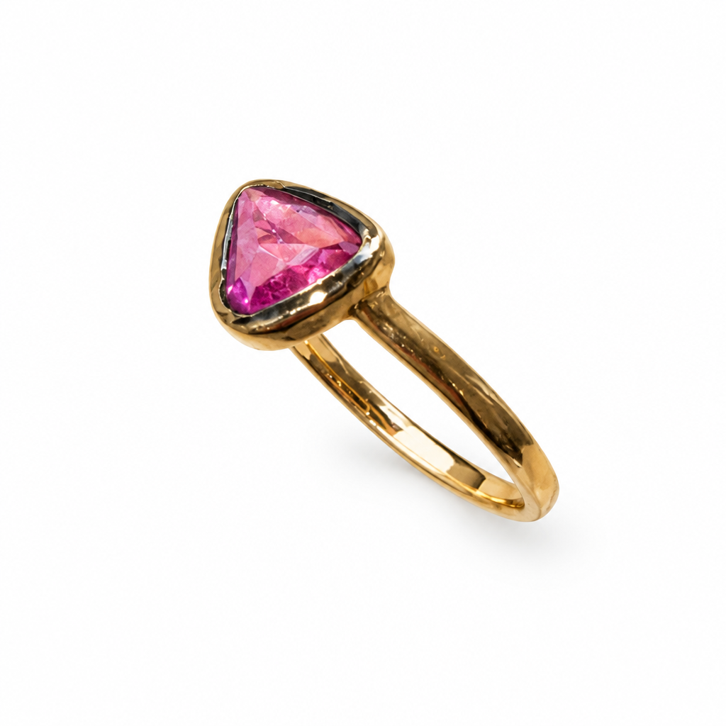 Gold ring with triangular pink stone, angled view on white background